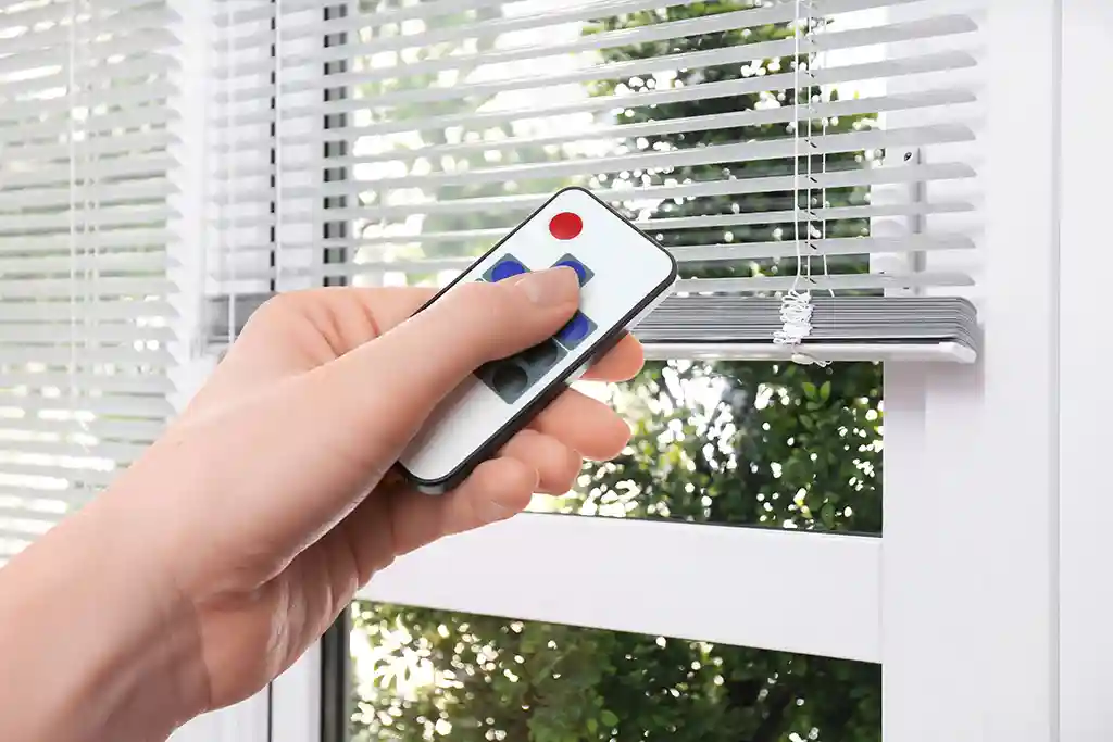 Hand mit einer Jalousie-Steuerung per Funkfernbedieung